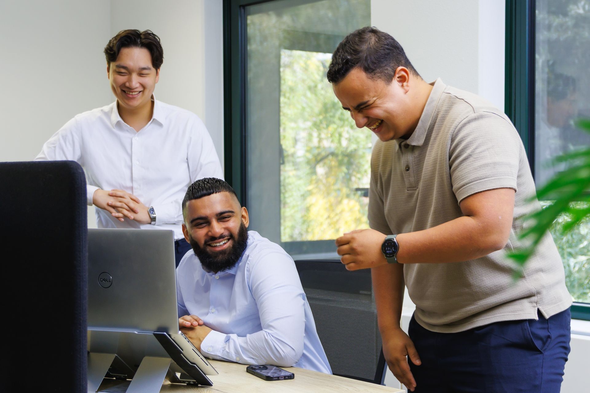 Drie collega’s die samenwerken achter een laptop in een kantooromgeving. Drie collega’s die samenwerken achter een laptop in een kantooromgeving.